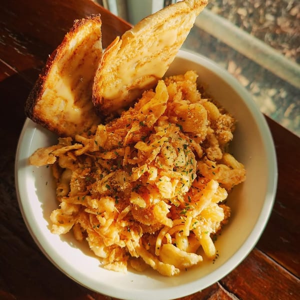 A white bowl of Beerline Cafe's vegetarian mac and cheese topped with crispy onions and grilled cheese.