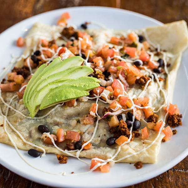A savory vegetarian crepe topped with avocado, diced tomatoes, black beans, and a creamy drizzle.